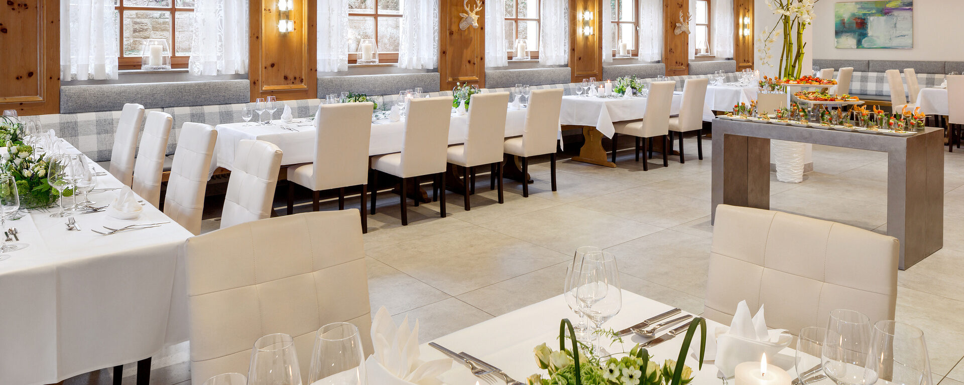 Für eine Feierlichkeit sind eine menge Tische mit weißer Dekoration verziert