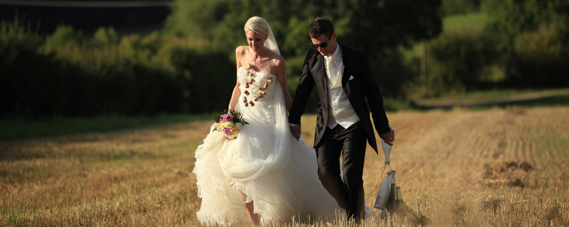 Ein Brautpaar läuft durch ein Feld