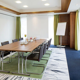 Ein kleiner Konferenzraum mit acht Stühlen und einer Leinwand