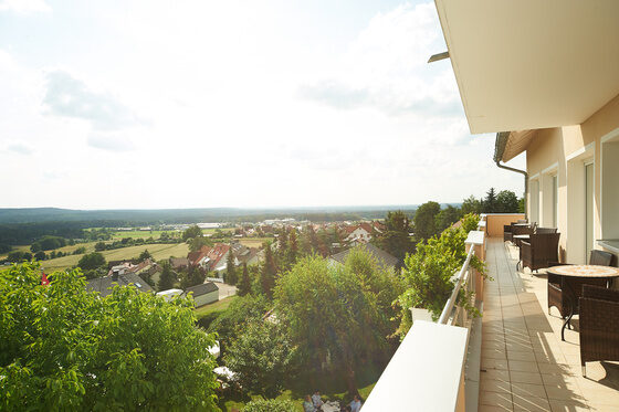 Auf dem Foto ist schön ein Balkon des Distlerhofs mit kleinen Tischen und Stühlen zu erkennen