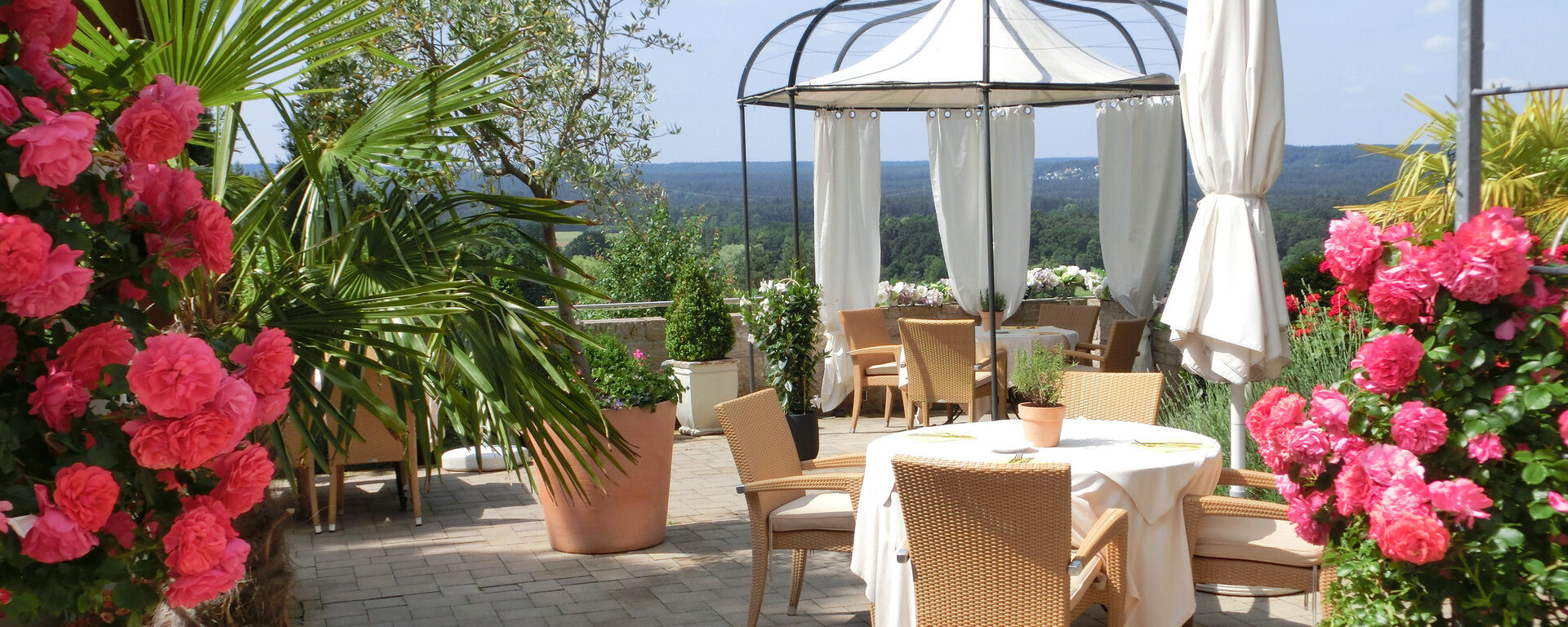 Die mit Blumen geschmückte Terrasse des Distlerhofs bietet Plätze zum Essen in der Sonne mit Blick über das Nürnberger Land