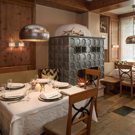 Auf dem Bild ist ein rustikales Esszimmer mit einem Tisch an einer Eckbank und einem Kamin zu sehen